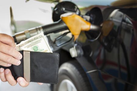 man counting money with gasoline refueling car at fuel stationの写真素材