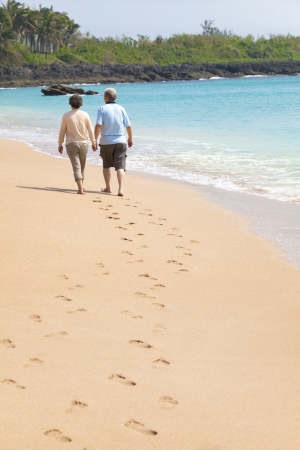 happy senior walking on the beach with footprintの写真素材