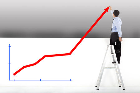 businessman standing on ladder drawing diagramsの写真素材