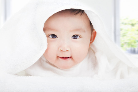 smiling baby smiling under a white blanket or towelの写真素材