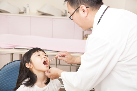 pediatrician examining  kid throat with  tongue depressor の写真素材
