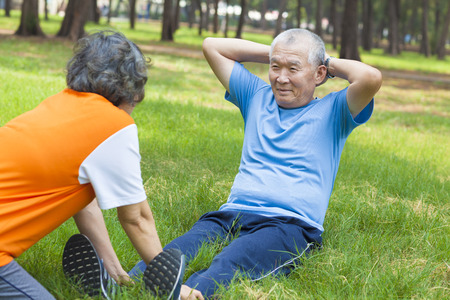 asian senior grandfather doing sit-ups in the parkの写真素材