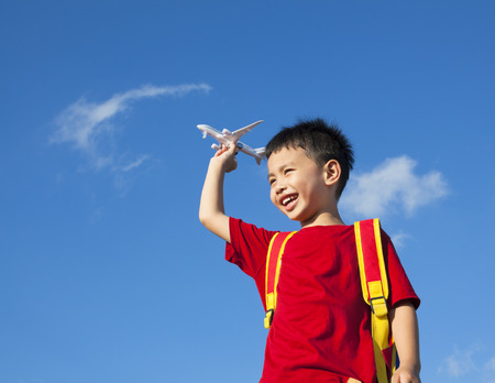little boy holding a airplane toy with a backpackの写真素材