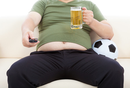 fat man drinking beer  and sitting on sofa to watch TVの写真素材