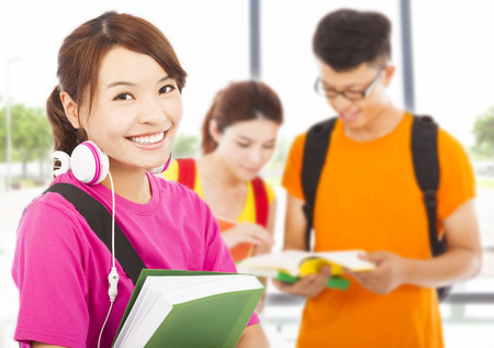 young student holding books and earphone with classmatesの写真素材