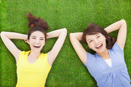 two smiling  young woman lying  on meadowの写真素材