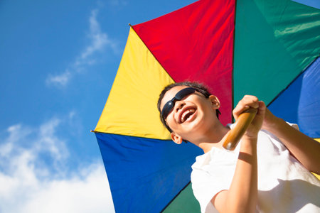 happy little boy hold a colorful umbrella with blue sky の写真素材