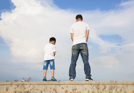 father and son standing on a stone platform and pee together の写真素材