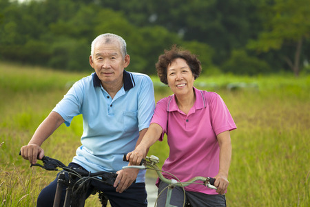 Happy Asian seniors couple biking in Park. retirement and health conceptの写真素材