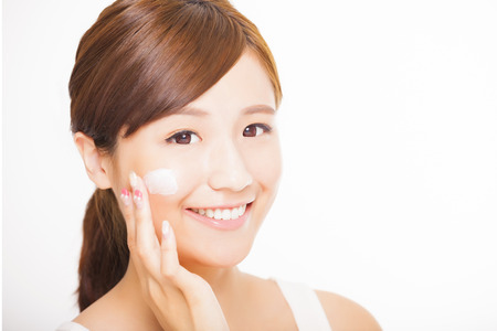 beautiful young woman applying cosmetic cream  on her faceの写真素材