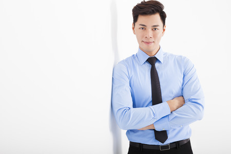young businessman leaning against white wall in officeの写真素材