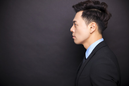 side view businessman standing before black backgroundの写真素材