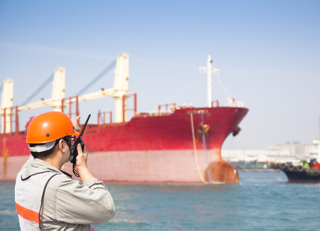 Harbor dock worker talking on  radio with ship backgroundの写真素材