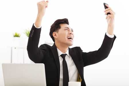 happy businessman watching the smart phone in  officeの写真素材