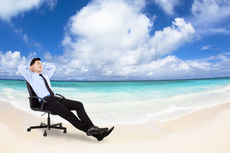 relaxed Young businessman sitting in a chair with beach backgroundの写真素材