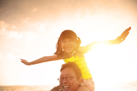Father and little girl playing on the beach at the sunsetの写真素材