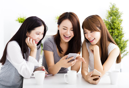happy young women watching smart phone  in living roomの写真素材