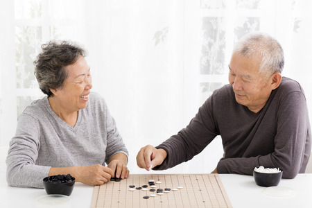 happy asian senior couple playing chess in living roomの写真素材