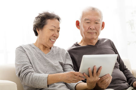 happy Senior Couple watching the tablet on sofaの写真素材