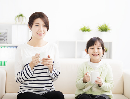 smiling mother and daughter on the sofaの写真素材