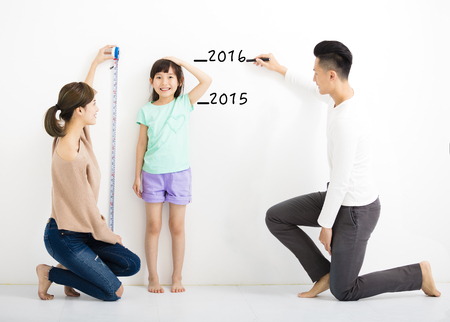 happy parent measures the growth of   daughterの写真素材