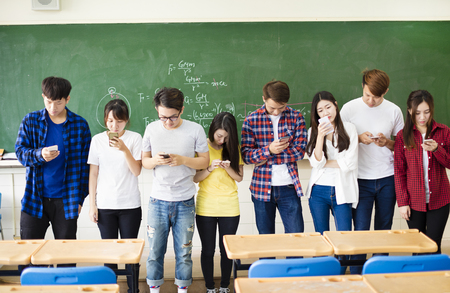 Group of students using smart mobile phones  in classroomの写真素材