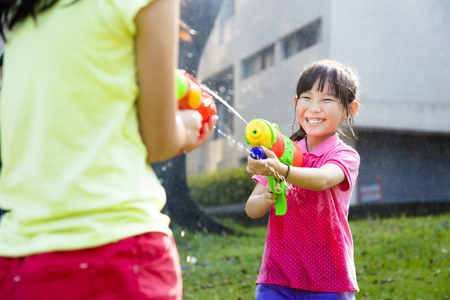 happy little girls  playing water guns in the parkの写真素材