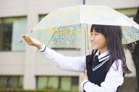 pretty  student girl holding umbrella  in the rainの写真素材