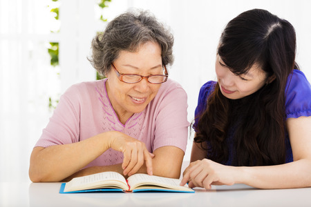 happy senior woman and  daughter  reading a bookの写真素材