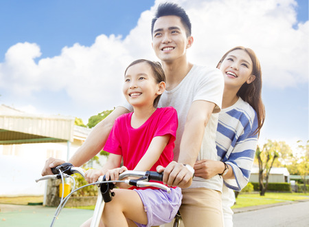 Happy asian family having fun in park with bicycleの写真素材