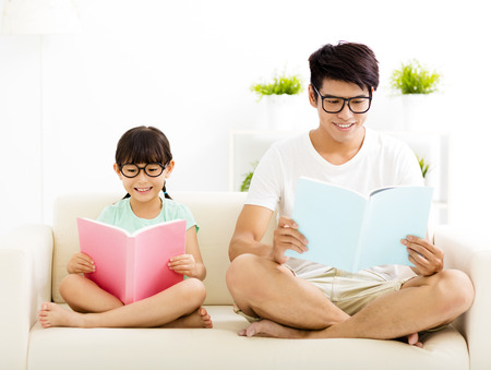father and daughter studying together on sofaの写真素材