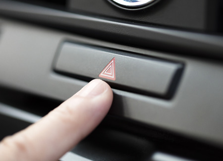 finger pressing car emergency light button