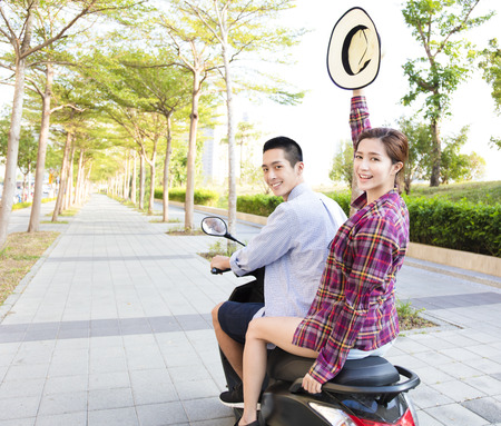 happy young couple riding  scooter in townの写真素材
