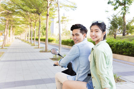 happy young couple riding  scooter in townの写真素材