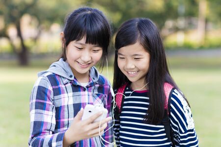 Two teenage girls friends watching the smart phone in schoolの写真素材
