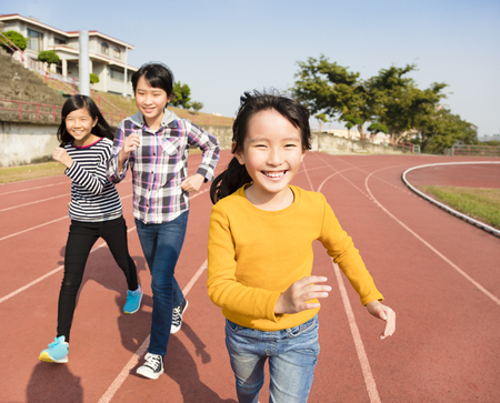 happy little girls running on the trackの写真素材