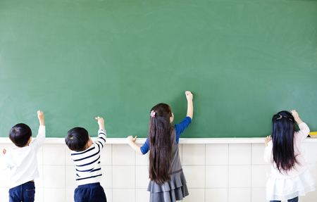 rear view of school students drawing on chalkboardの写真素材