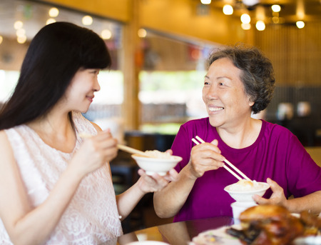 Happy  daughter and senior mother enjoy eating in restaurantの写真素材