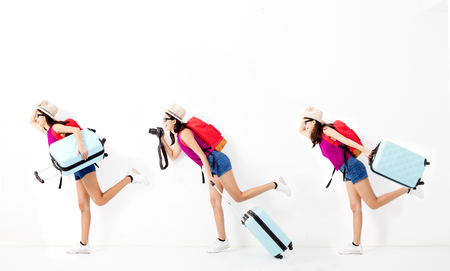 Happy young woman holding suitcase  and running for travelの写真素材