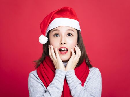 young christmas woman wearing santa hat and surprisedの写真素材