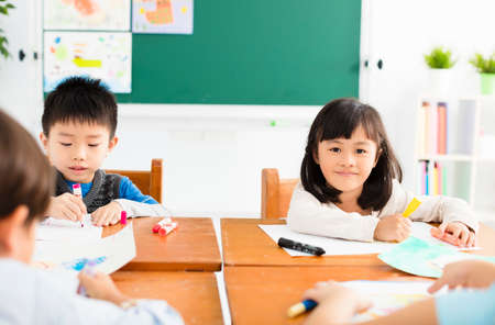 happy little girl drawing in the classroomの写真素材