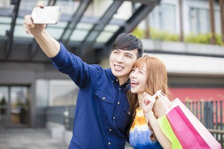 happy couple taking selfie in front of shopping mallの写真素材