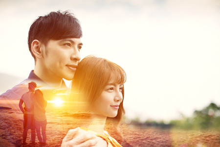 romantic young couple hugging and watching sunset on the beach の写真素材