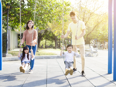 Happy Asian family playing swing togetherの写真素材