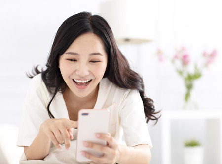 happy woman sitting on couch and watching smart  phoneの写真素材