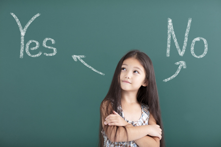 beautiful little girl thinking before chalkboardの写真素材