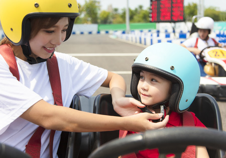 Mother attaching daughters  helmet on go kart race trackの写真素材