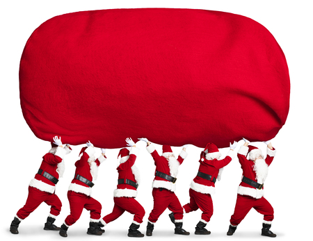 many Santa claus carrying big and heavy gift red sackの写真素材