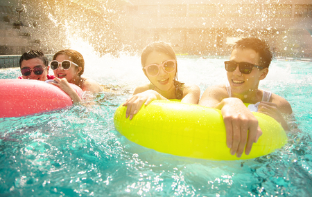 Happy friends playing in swimming pool on summer vacationの写真素材