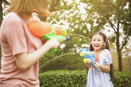 mother and little girls playing water guns in the parkの写真素材